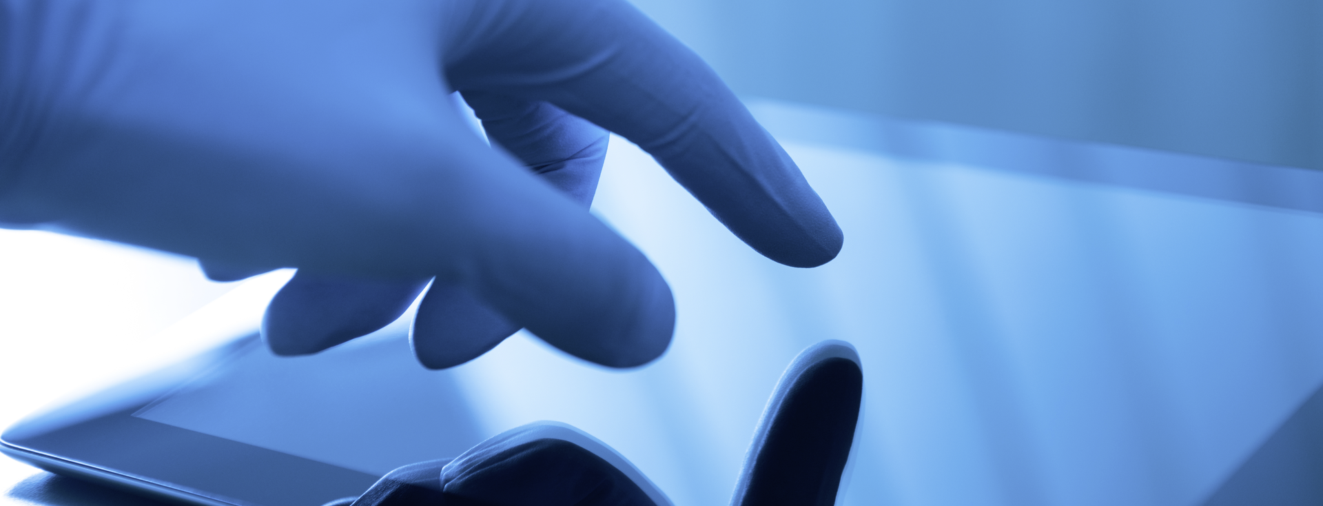 hand wearing a latex glove operates a touchscreen